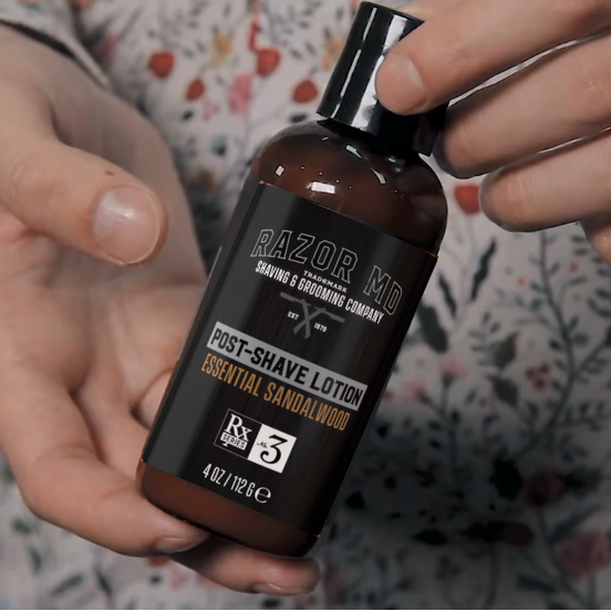 Razor MD post-shave lotion bottle held by a person with a floral patterned fabric background