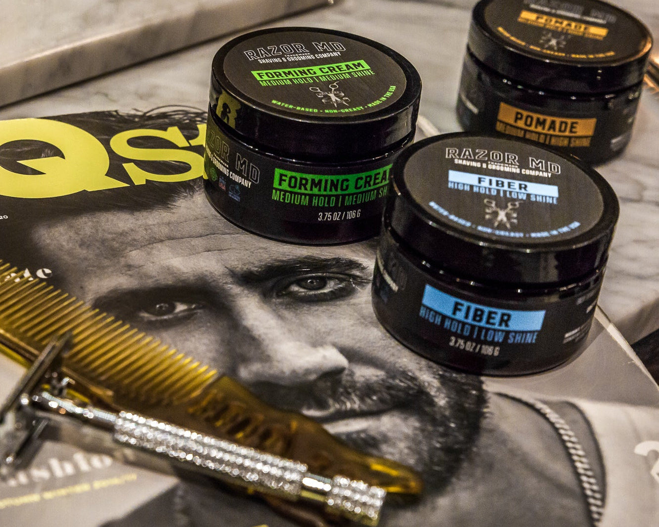 Three jars of RAZOR MD pomade on a magazine with grooming tools